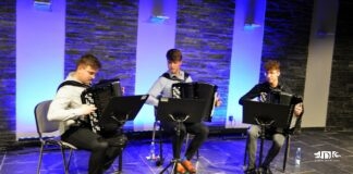 Obraz zawiera: trzech akordeonistów gra na instrumentach wpatrując się w zapisy nutowe umieszczone na pulpitach przed nimi.