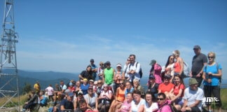 Grupowe zdjęcie uczestników wycieczki na szczycie Smereka. Siedzący z przodu trzymają flagę jasielskiego oddziału polskiego towarzystwa krajoznawczo turystycznego