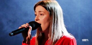 Granatowe tło sceniczne, na pierwszym planie karolina polak, solistka jasielskiego domu kultury w czerwonej sukience śpiewa do mikrofonu