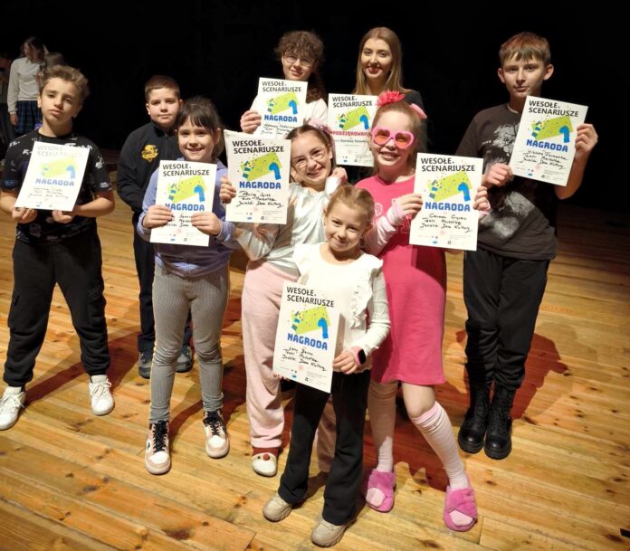 1000014825 dziecięca grupa teatralna wraz ze swoją instruktorką stoi na scenie z dyplomami za zwycięstwo w konkursie teatralnym