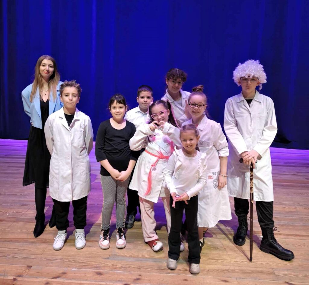 Na scenie stoi grupa dzieci z teatru jasielskiego domu kultury wraz ze swoją instruktorką