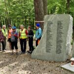 rowerzyści na cmentarzu w Warzych przy tablicach ofiar terroru hitlerowskiegoI