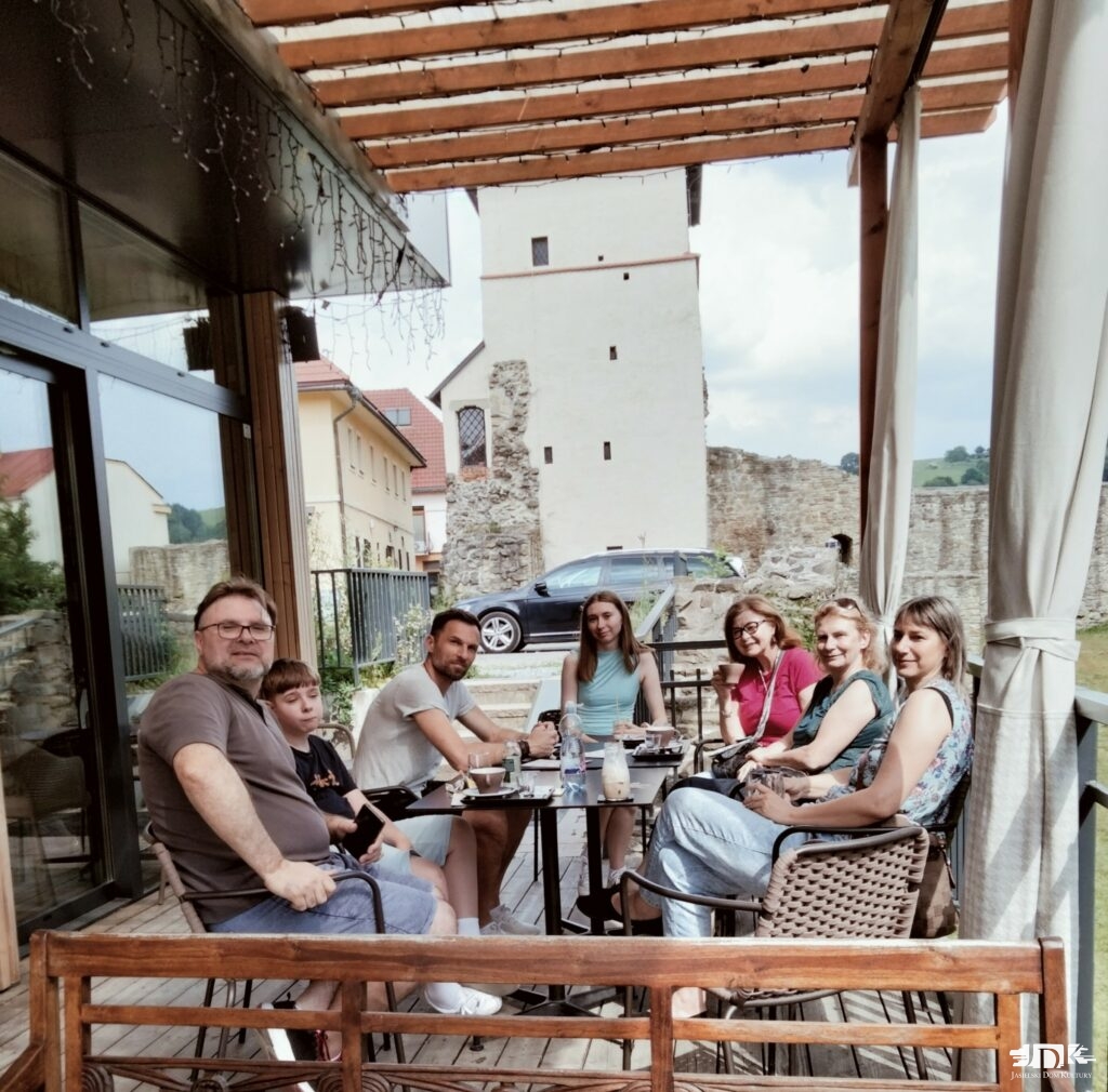 grupa osób siedząca na tle zamku