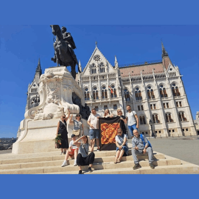 Wystawa batików w Budapeszcie Grupa osób na tle pomnika w Budapeszcie