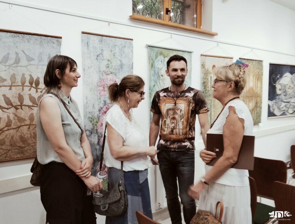 Grupa osób na tle batików