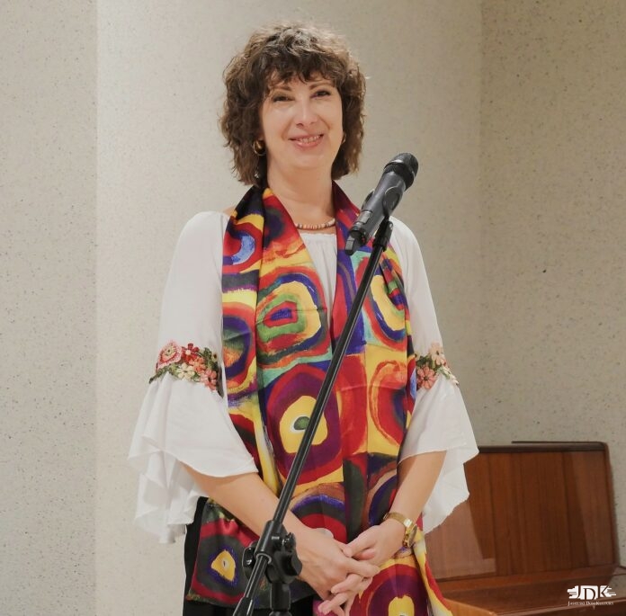 Adriana Holender w barwnym szalu i białej bluzce