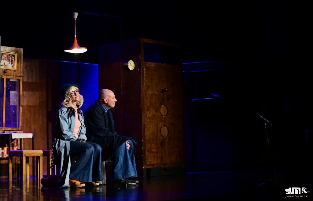 siedzący na ławce bohaterowie, w tle ciemno