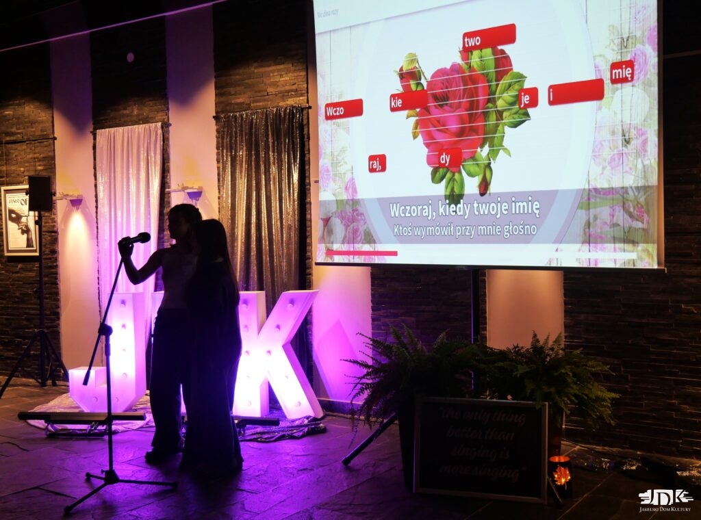 duet śpiewa piosenkę, a w tle ekran z wyświetlanym tekstem utworu