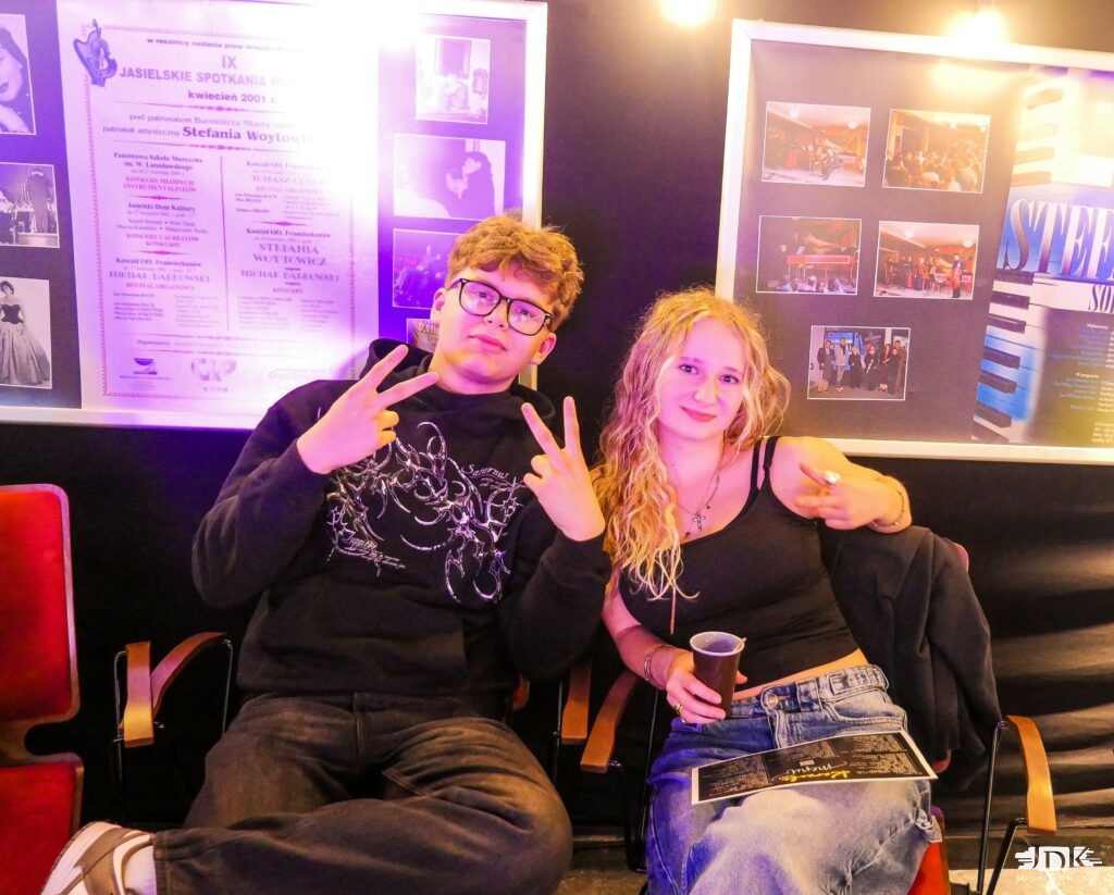 chłopak i dziewczyna pozują do zdjęcia. w tle ściana z obrazami