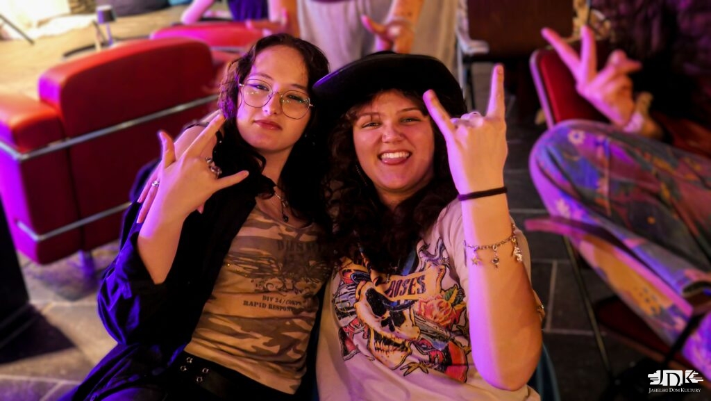 dwie uczestniczki karaoke - jedna w okularach, a druga w kapeluszu, pozują do zdjęcia