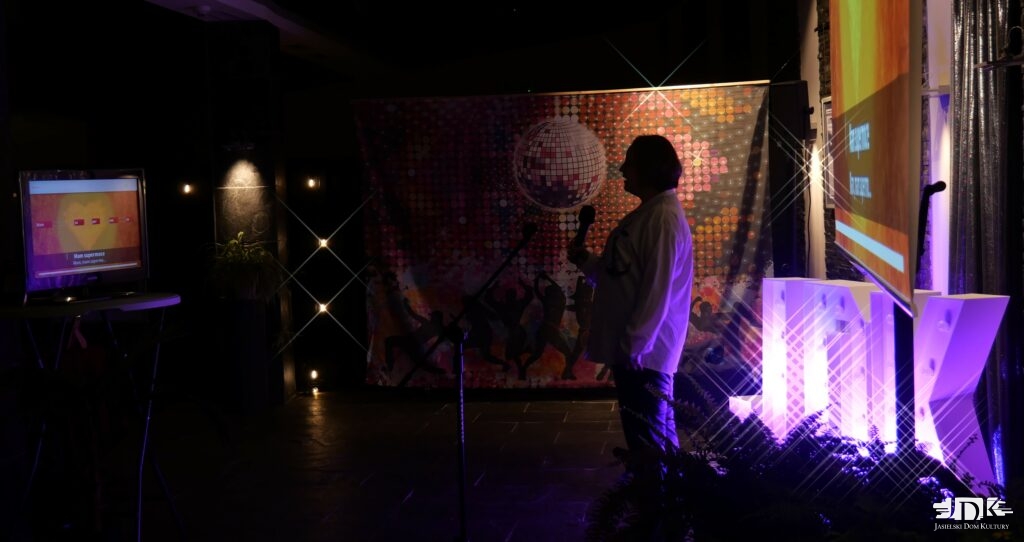 dziewczyna śpiewa piosenkę, w tle litery JDK