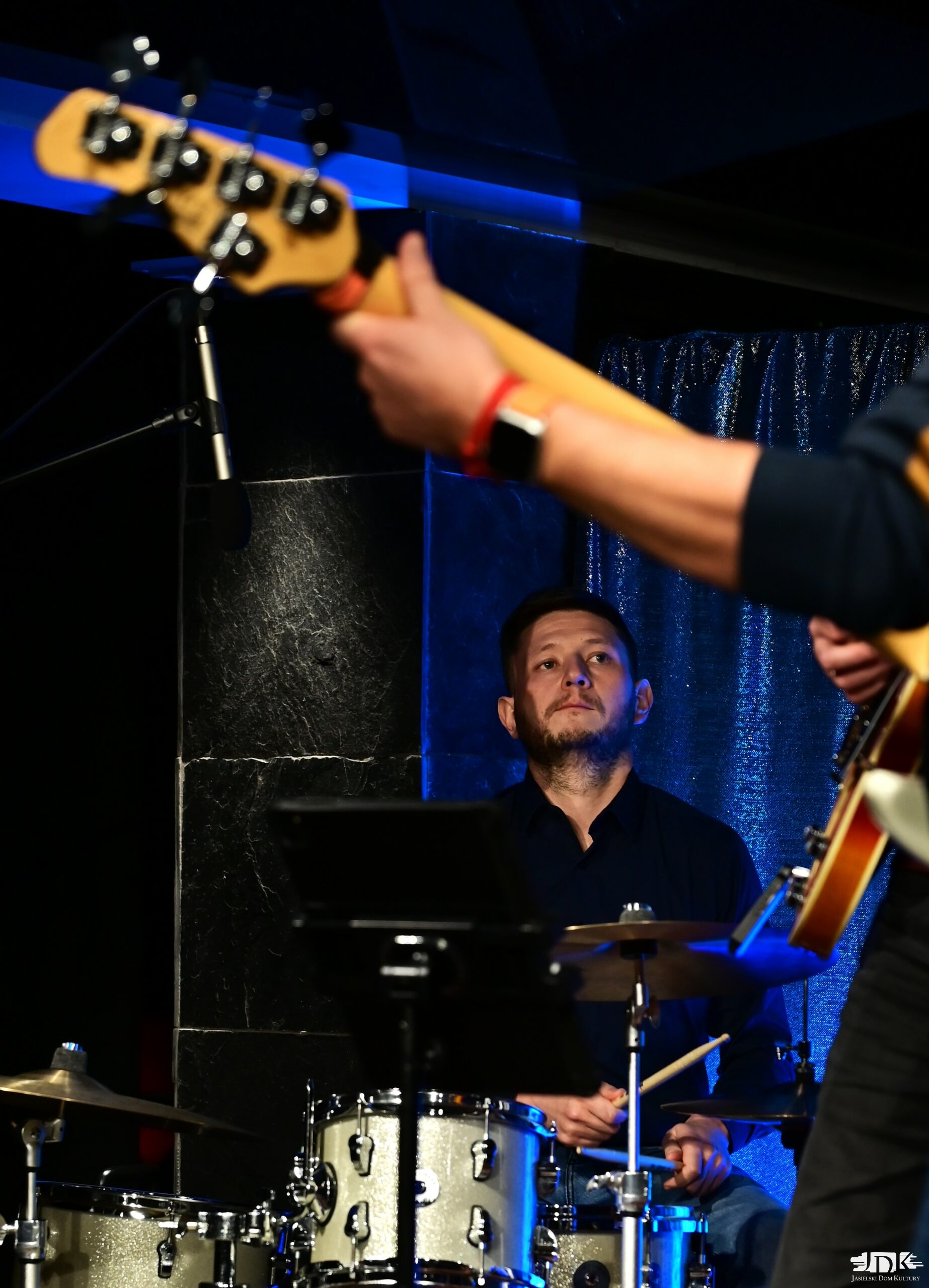 perkusista a w tle czarna ściana i niebieski materiał