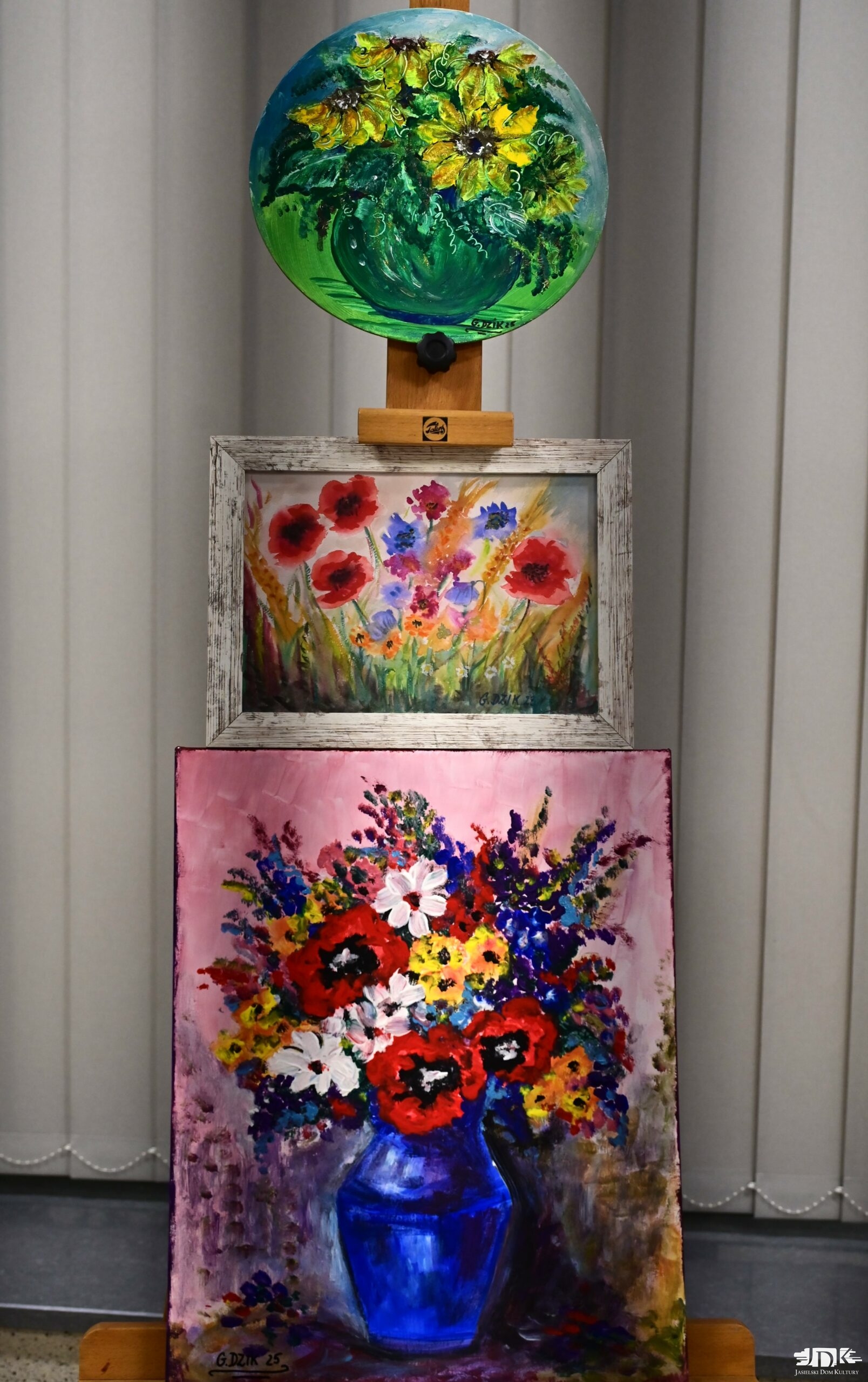 trzy obrazy o tematyce florystycznej, jeden na drugim na sztaludze