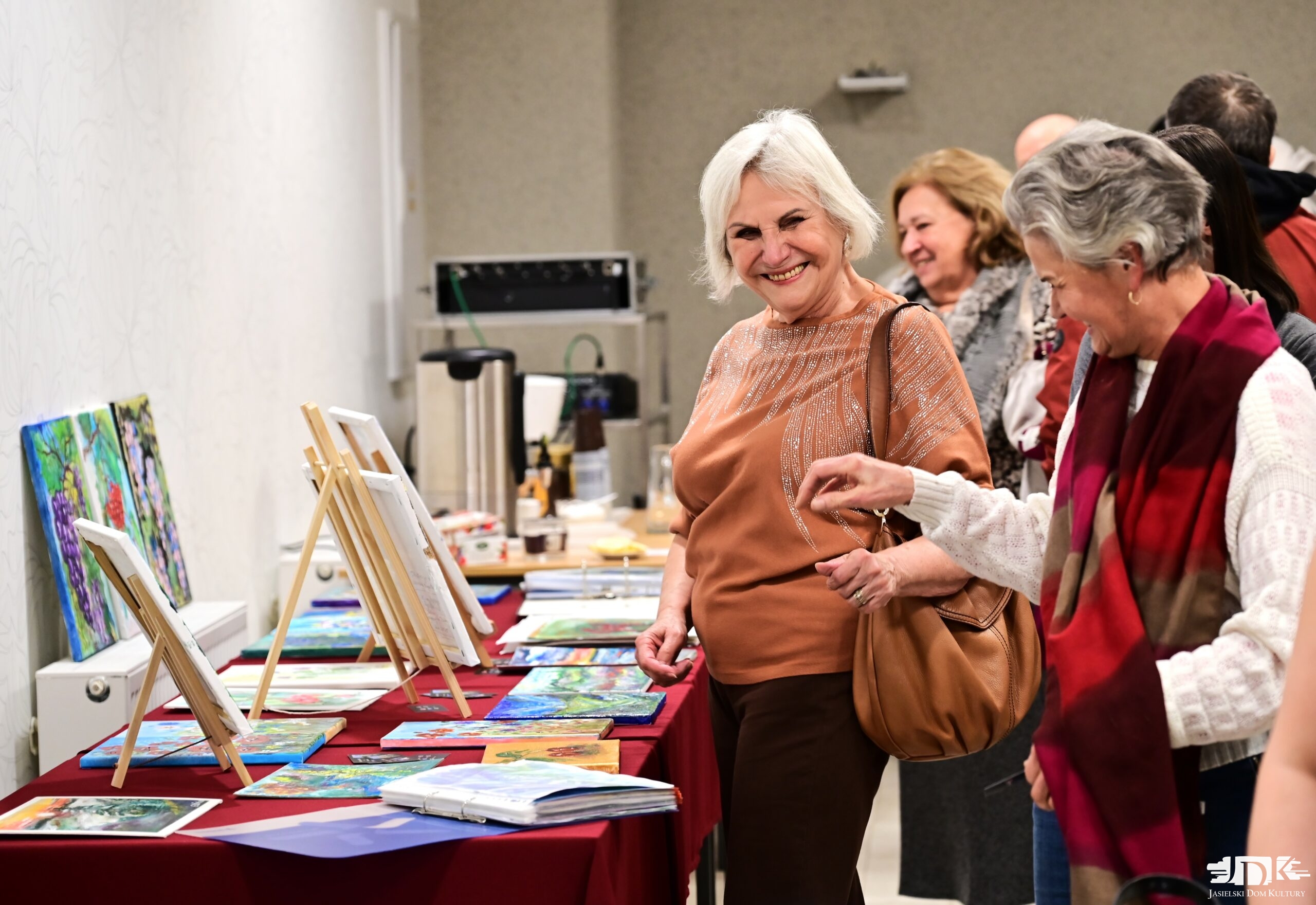 usmiechnięci uczestnicy spotkania oglądają katalog obrazów