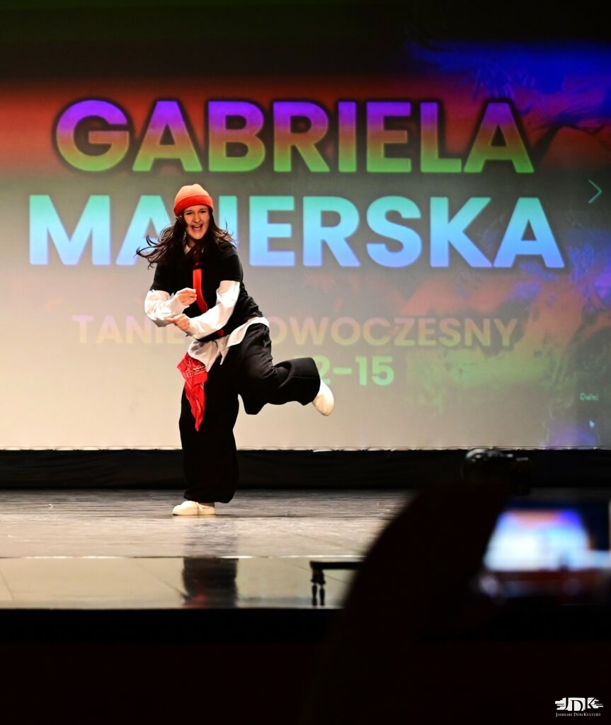 uśmiechnięta tancerka podnosi jedną nogę ku górze