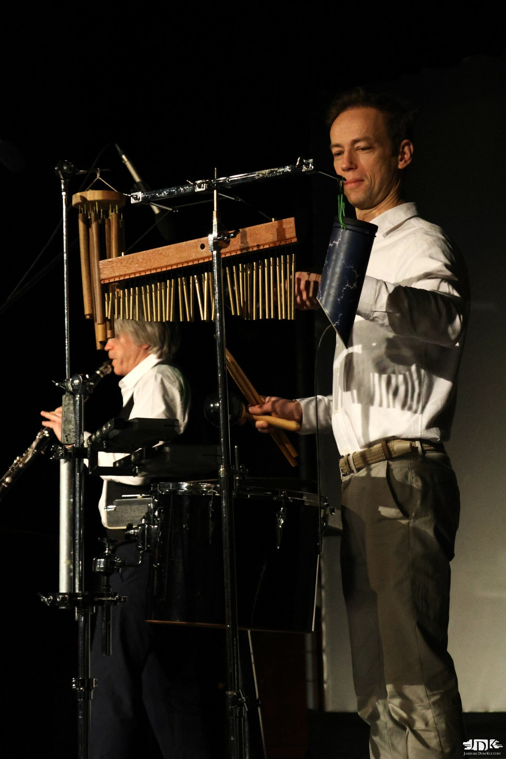 muzyk w białej koszuli grający na dzwonkach