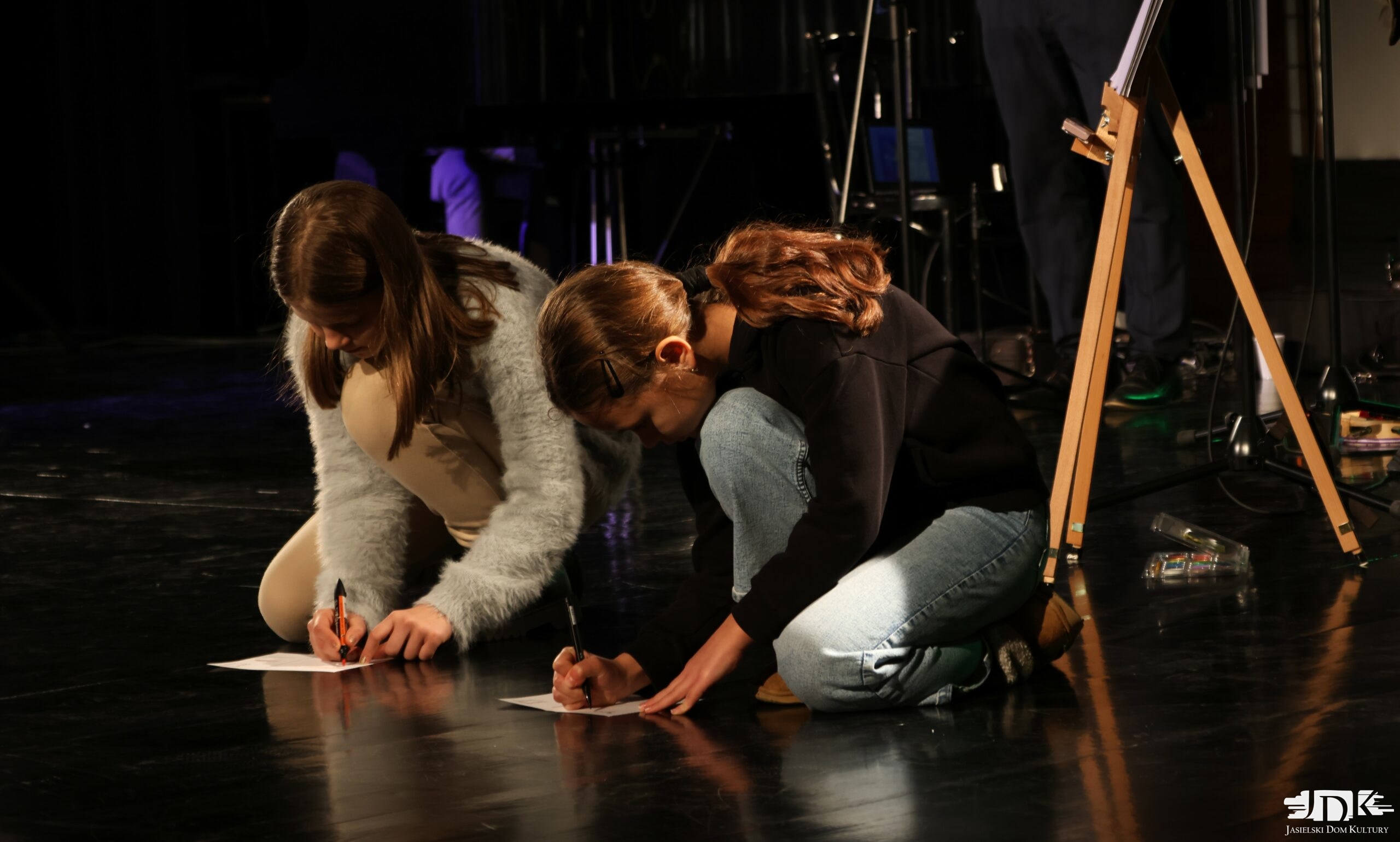 dwie dziewczynki kucają i piszą na kartkach swoje wspomnienia