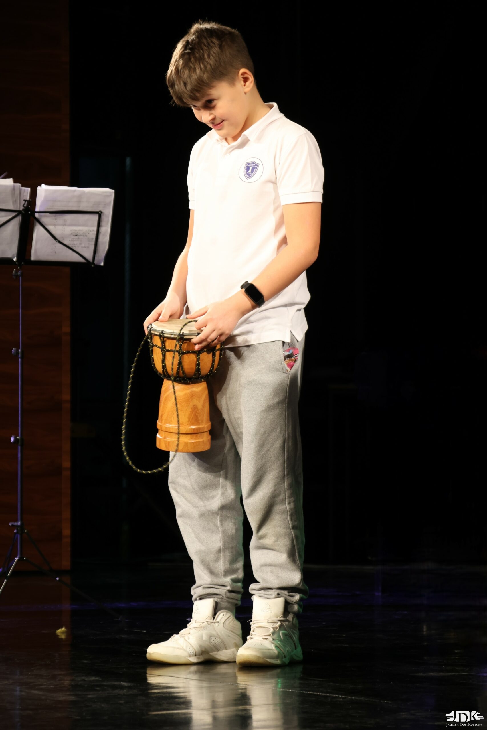 uśmiechnięty chłopiec w białym mundurku, trzymający bongos