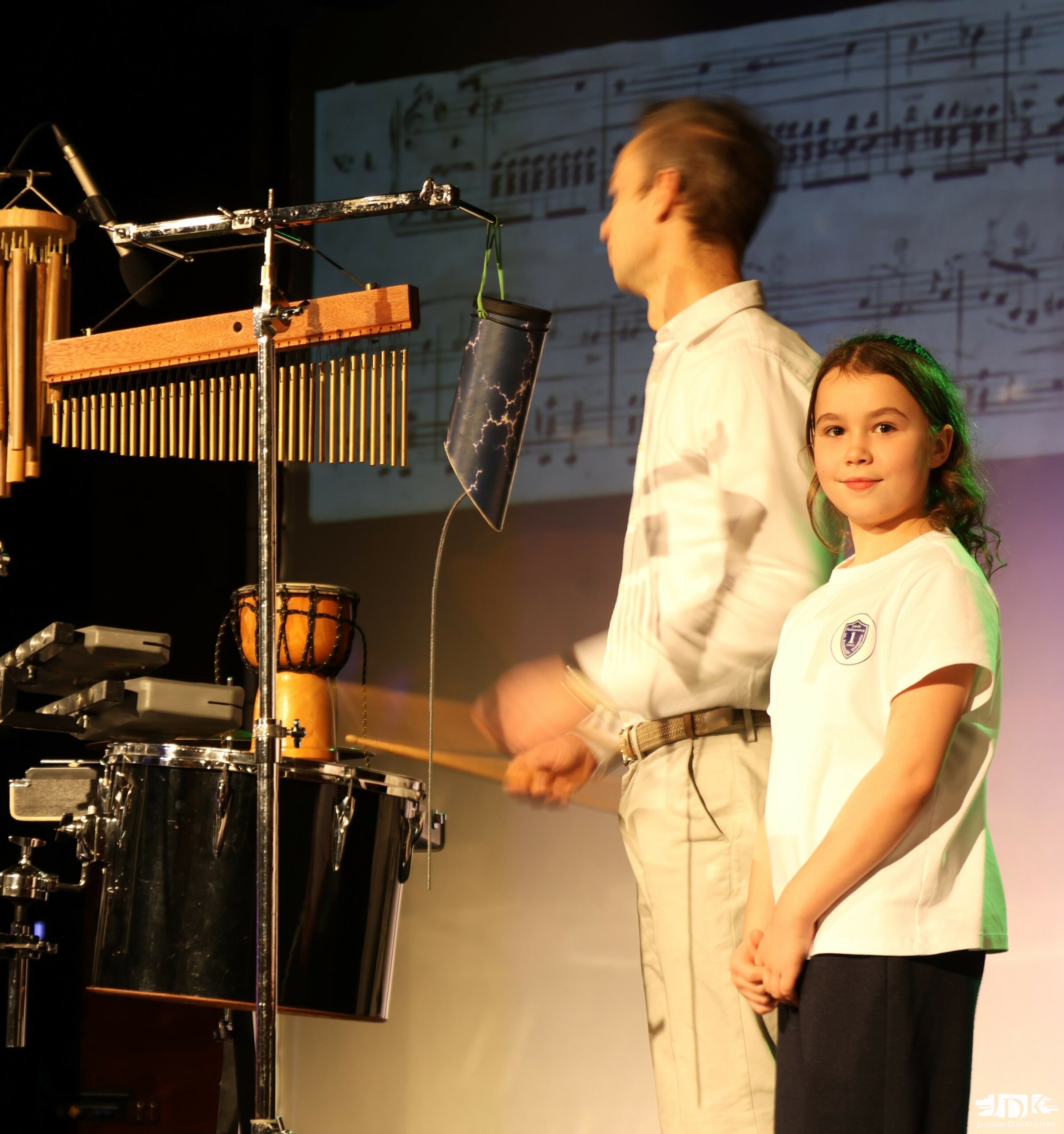 dziewczynka przy zestawie perkusyjnym spogląda w aparat