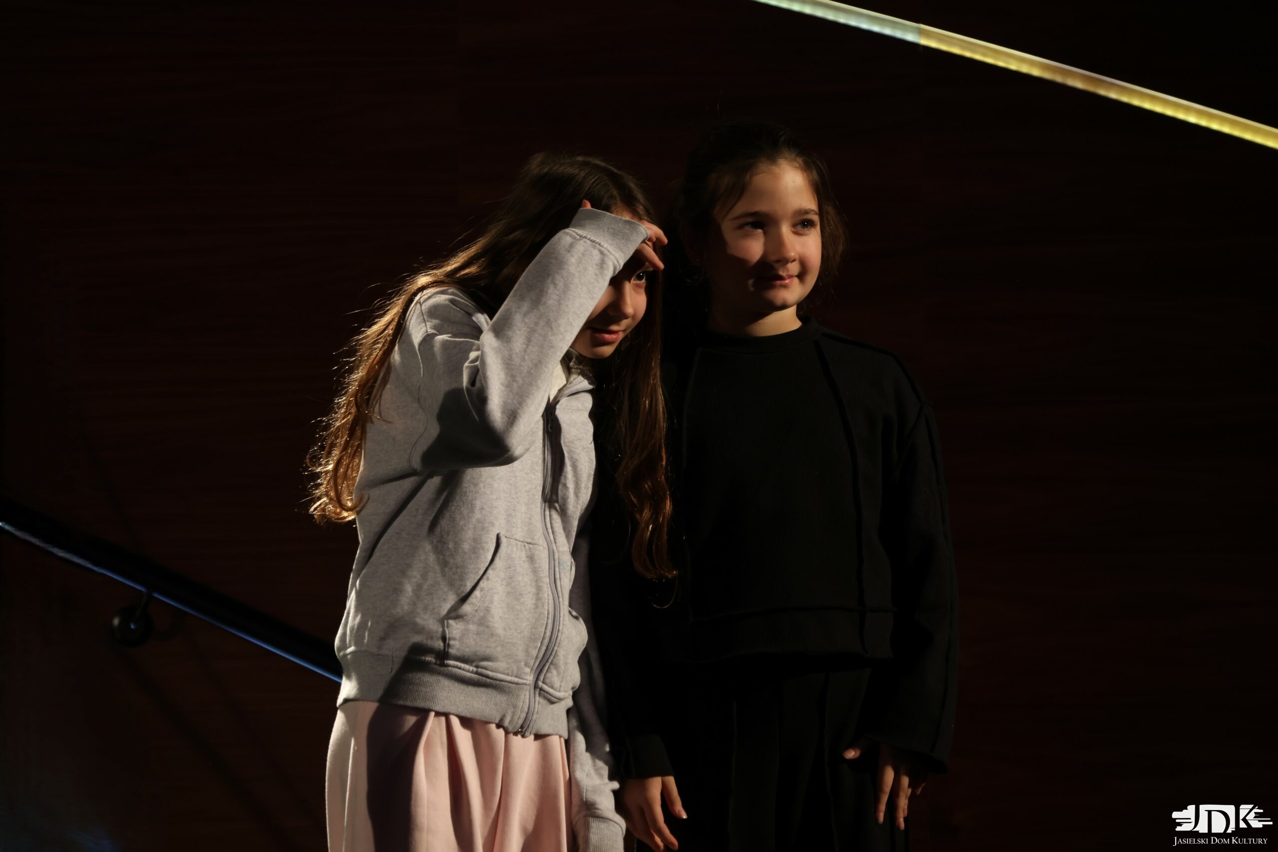 dwie dziewczynki spoglądające na publiczność, uśmiechają się lekko