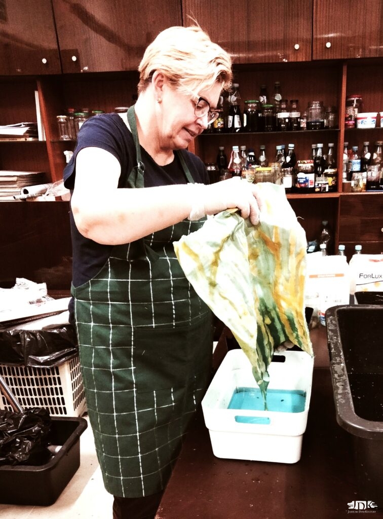 pani wyciąga materiał z kuwety z farbą