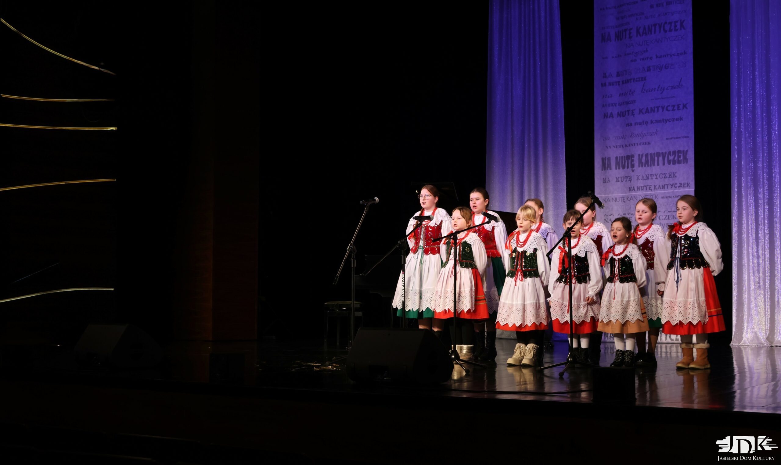 10 dziewczynek w ludowych strojach i czerwonych koralach