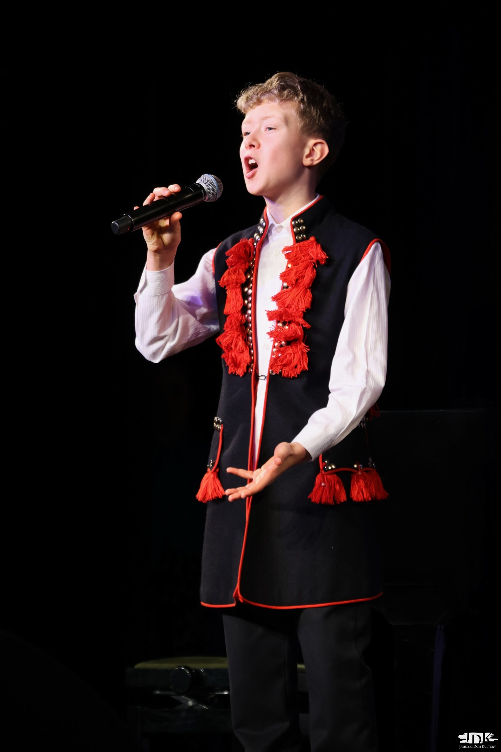 chłopiec w czarnej długiej kamizelce z czerwonymi chwostami