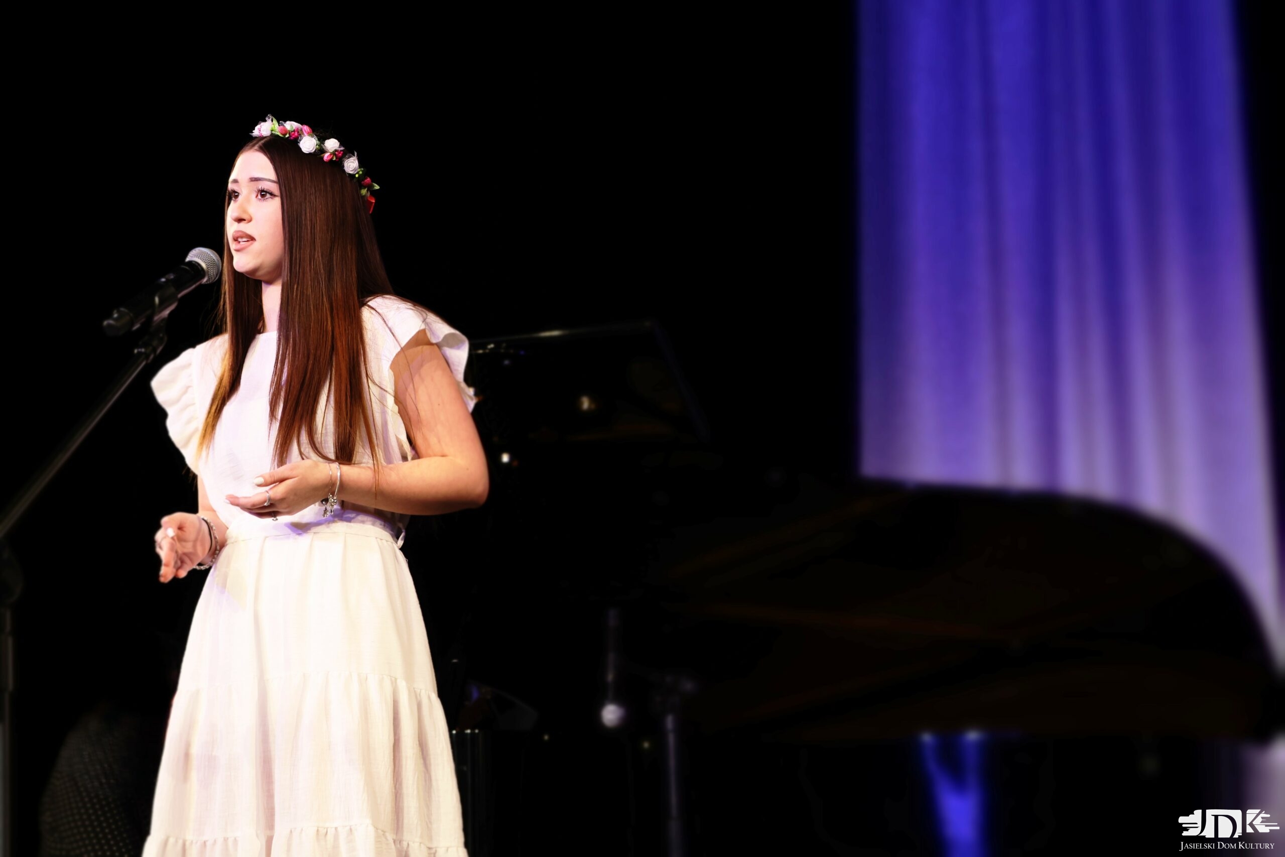 dziewczyna śpiewająca w białej sukience oraz kwietnym wianku