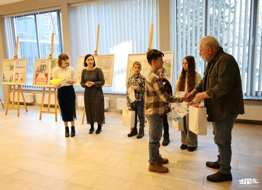 na pierwszym planie plastyk JDK wręcza nagrodę chłopcowi. W tle troje nagrodzonych dzieci oraz pani dyrektor JDK i instruktorka plastyki