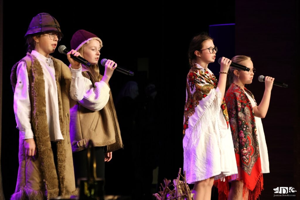 cztery dziewczynki: dwie w białych sukienkach oraz dwie w kożuchach