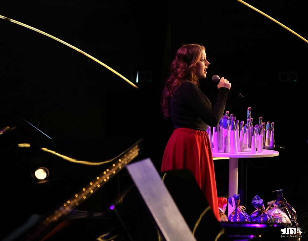 dziewczynka w czerwonej spódnicy i czarnej bluzce - w tle statuetki anioły