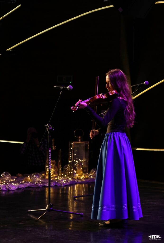 dziewczyna w niebieskiej spódnicy i czarnej bluzce gra na skrzypcach