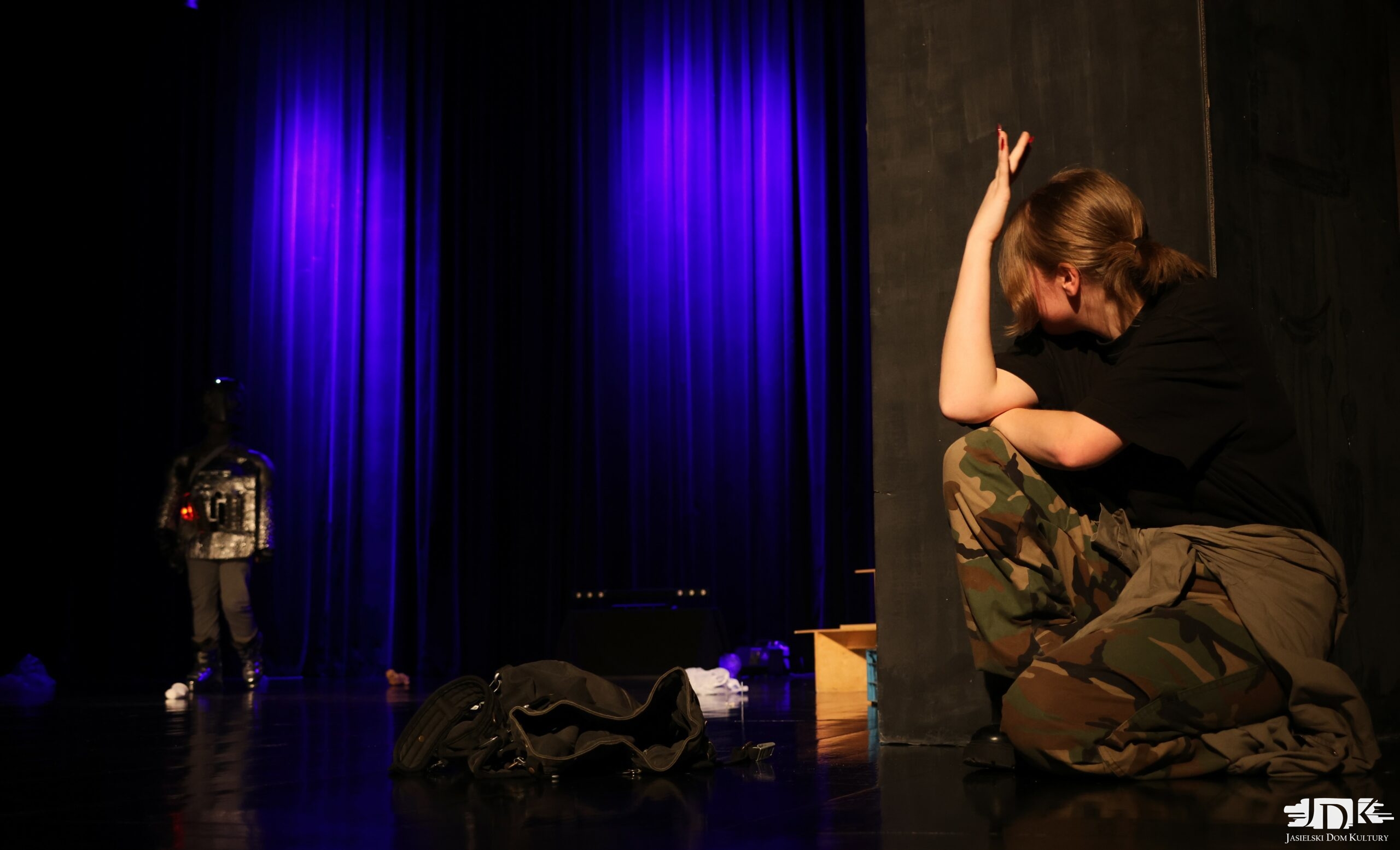 kucająca dziewczyna w spodniach moro w prawej części zdjęcia. w tle robot