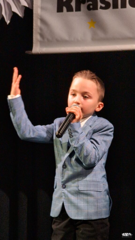 chłopiec w niebieskiej marynarce z uniesioną ręką