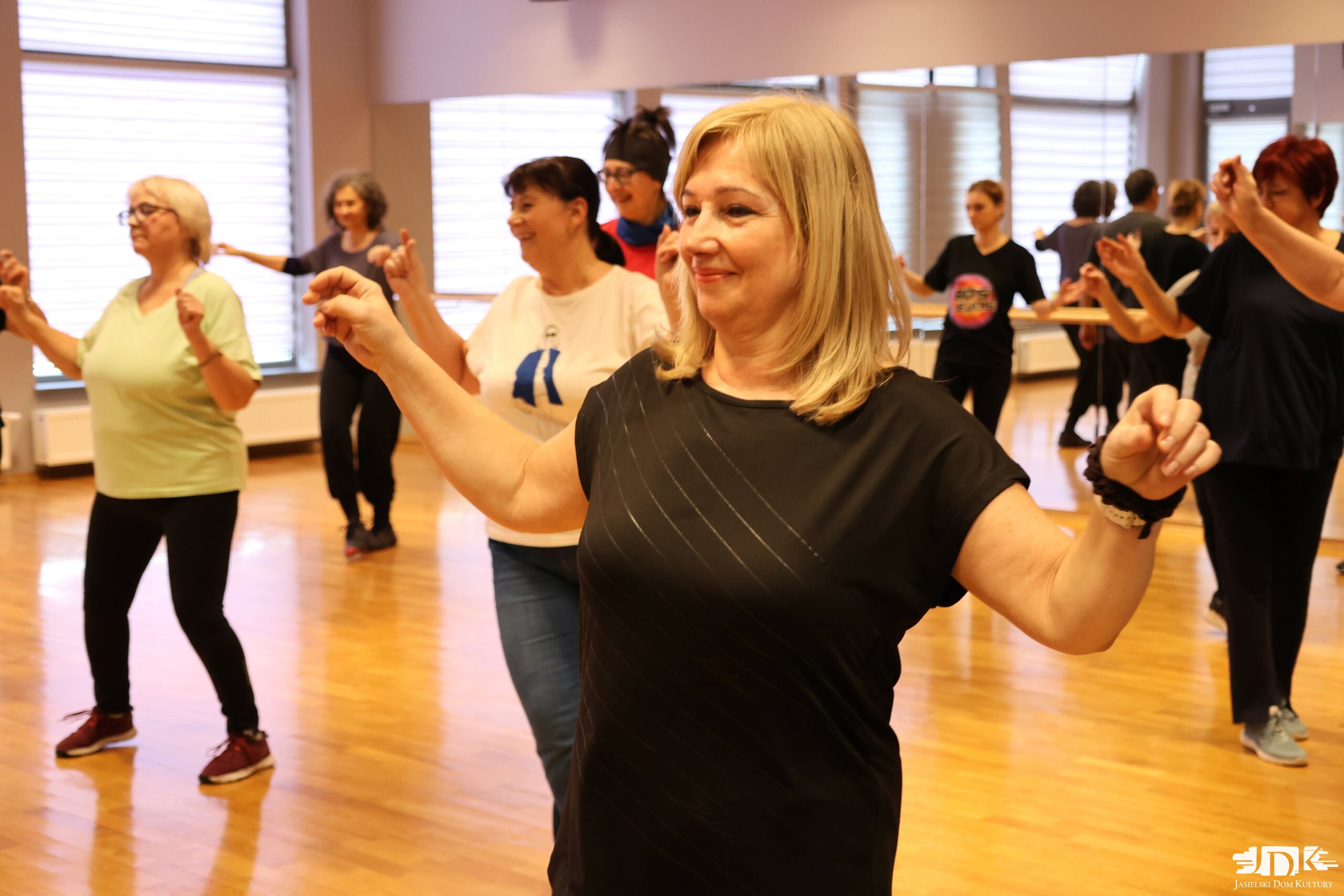 uczestnicy warsztatów z rękami ku górze, tańczący greckie tańce