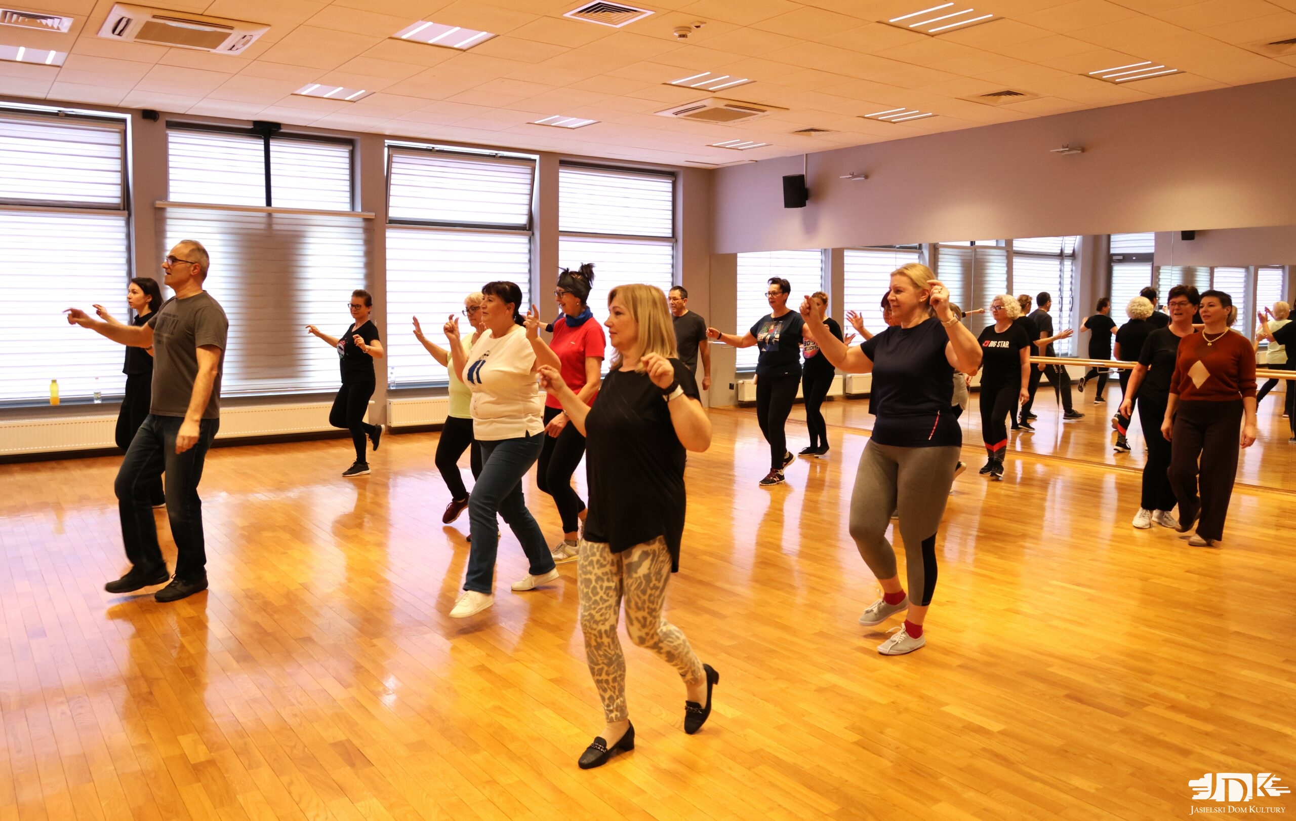uczestnicy warsztatów z rękami ku górze, tańczący greckie tańce