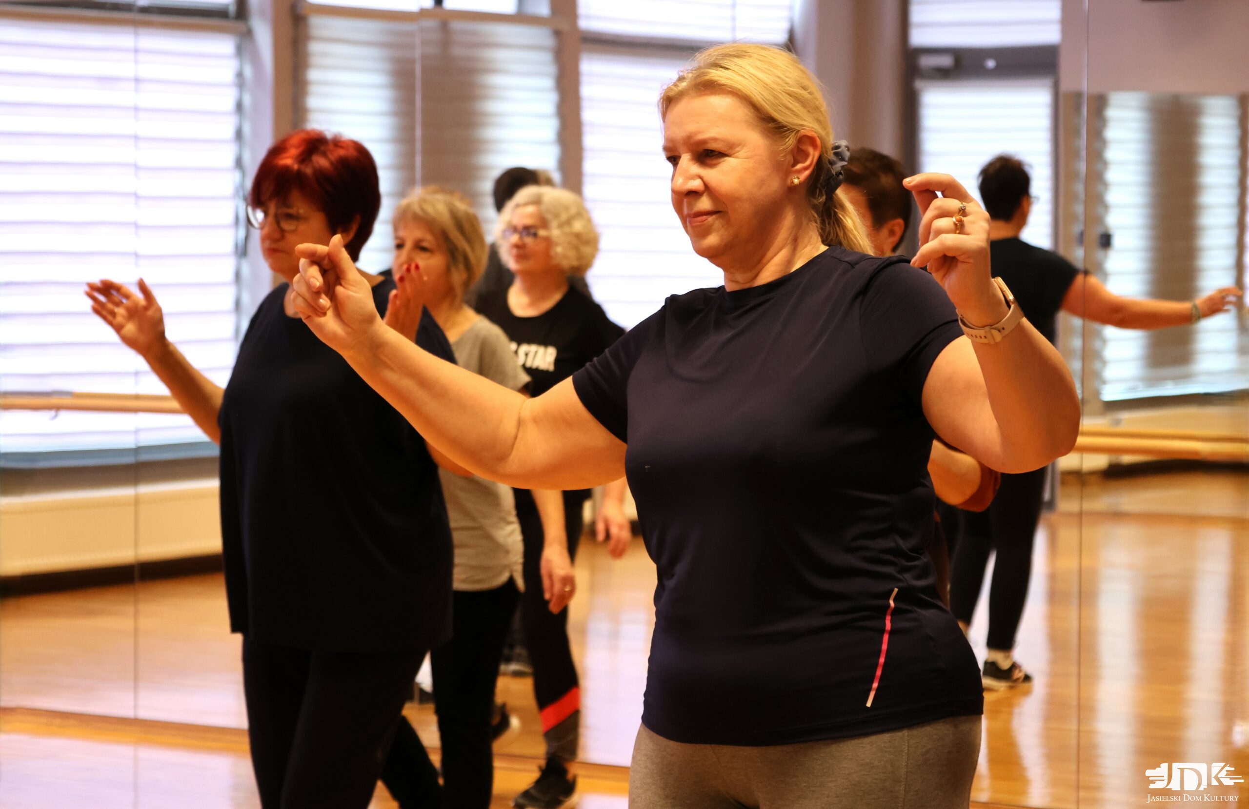 uczestnicy warsztatów z rękami ku górze, tańczący greckie tańce