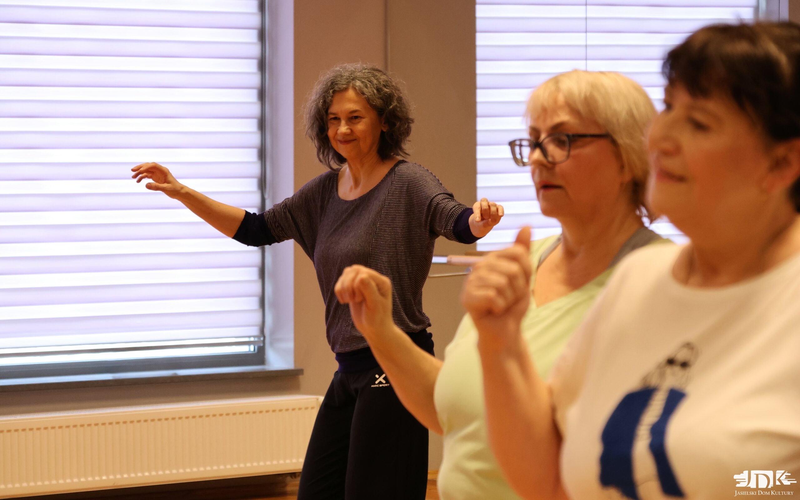 uczestnicy warsztatów z rękami ku górze, tańczący greckie tańce