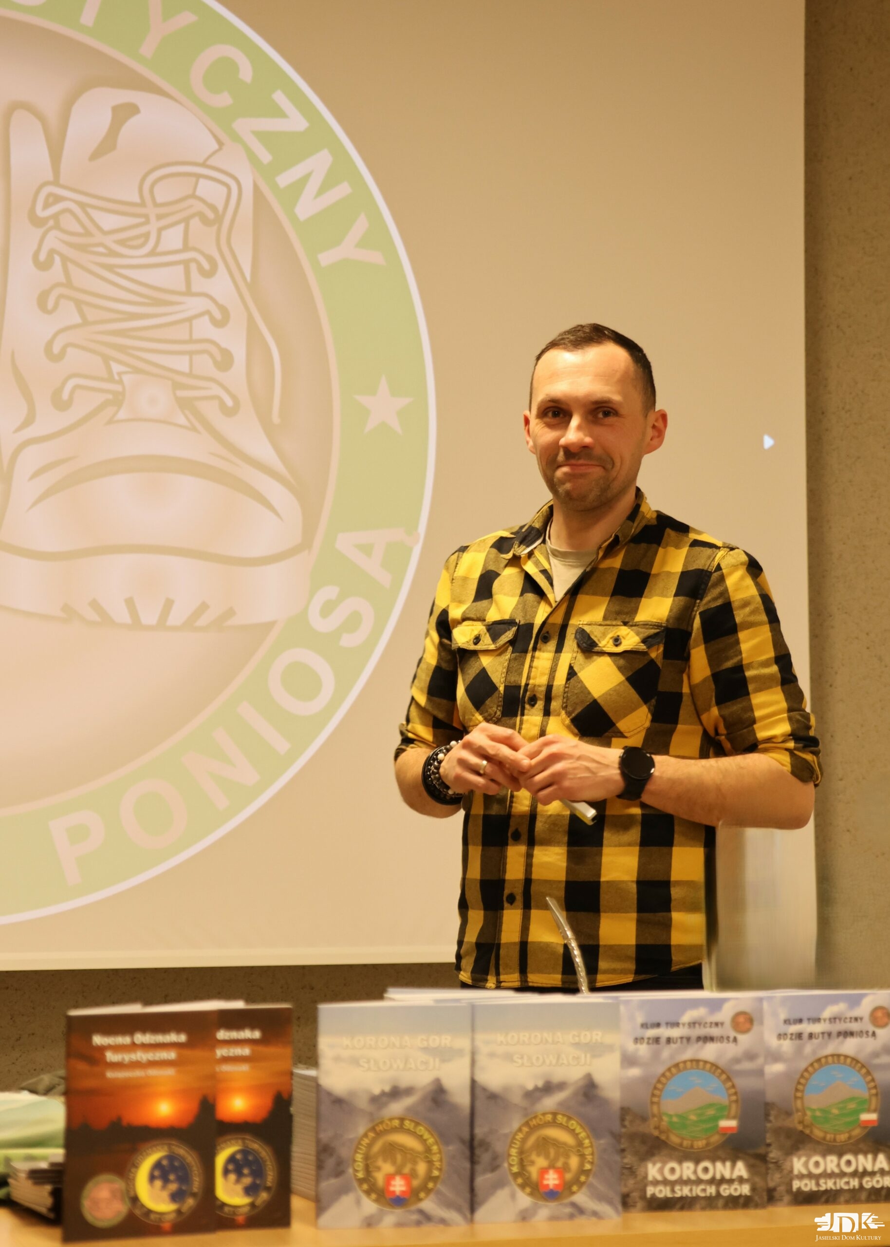 bohater spotkania w żółtej koszuli w czarną kratę uśmiecha się do obiektywu