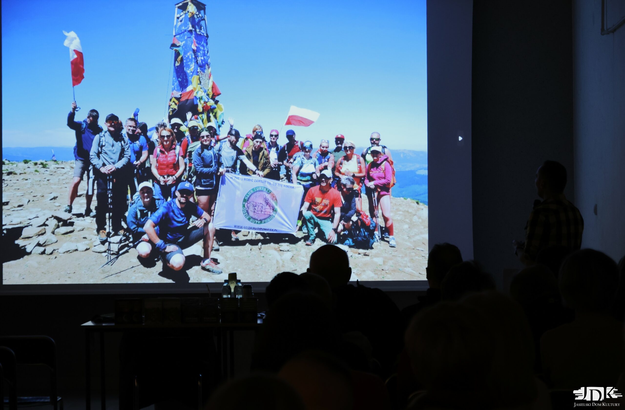 grupa turystów na szczycie pozuje z flagą organizacji turystycznej "gdzie buty poniosą: