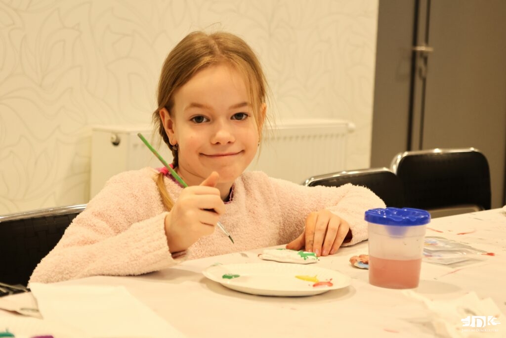 dziewczynka malująca figurki gipsowe uśmiecha się do obiektywu