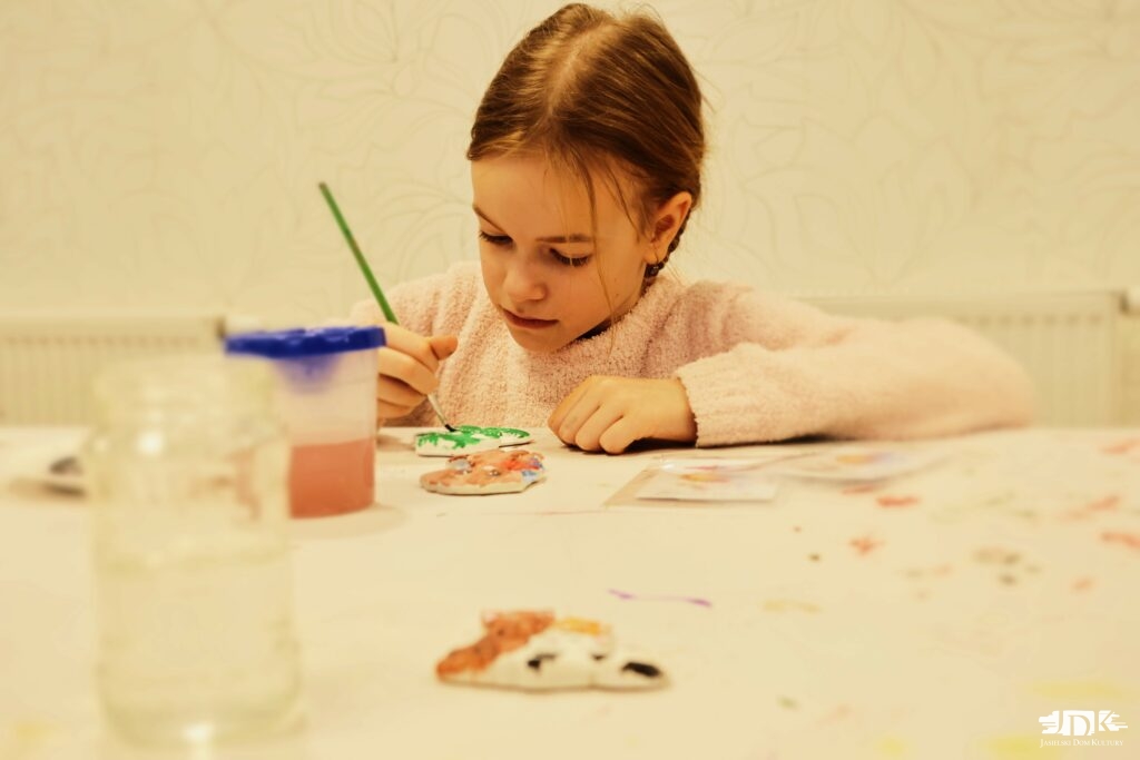 dziewczynka malująca figurki gipsowe uśmiecha się do obiektywu