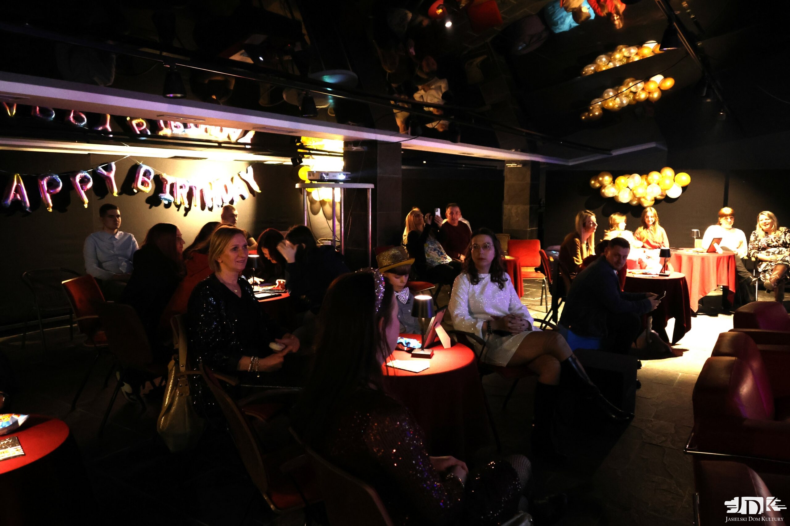 pełna sala ludzi, udekorowana balonami