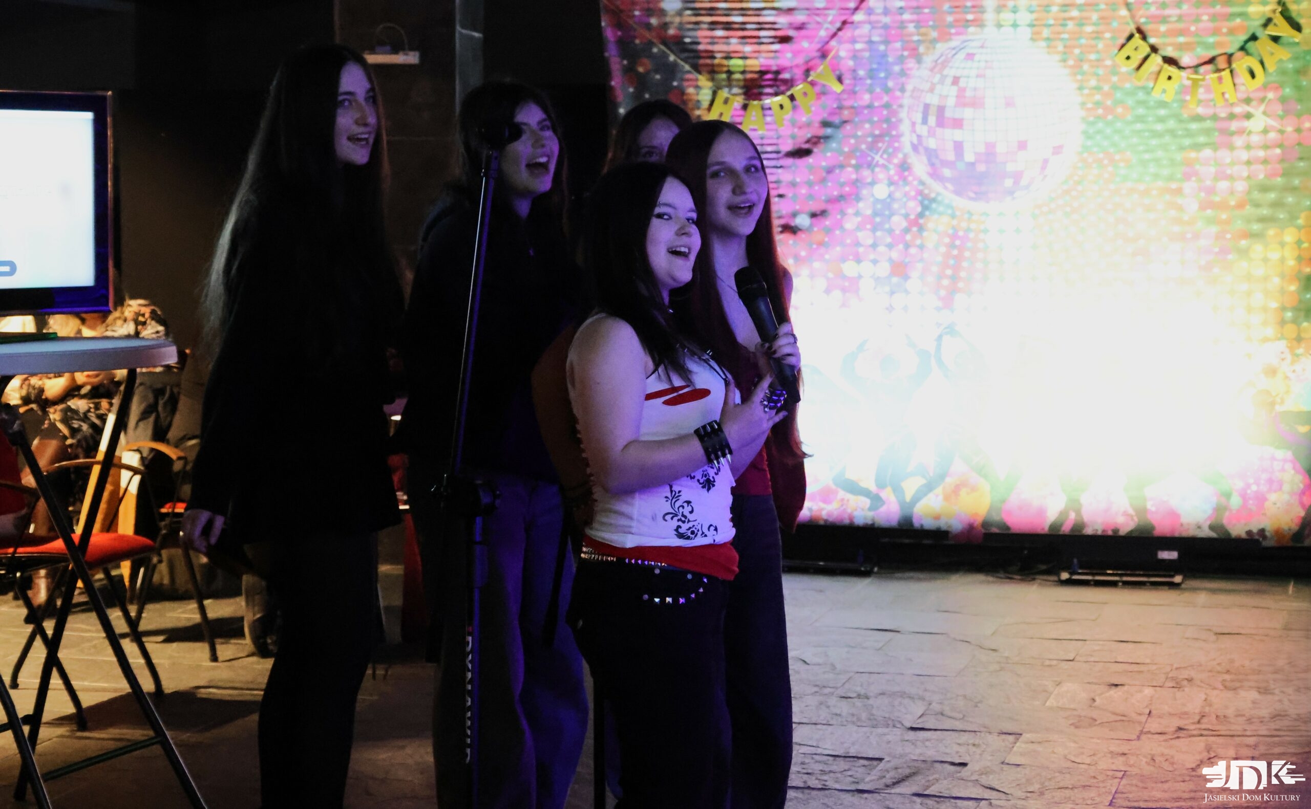 grupka pięciu dziewcząt śpiewająca i patrząca do kamery