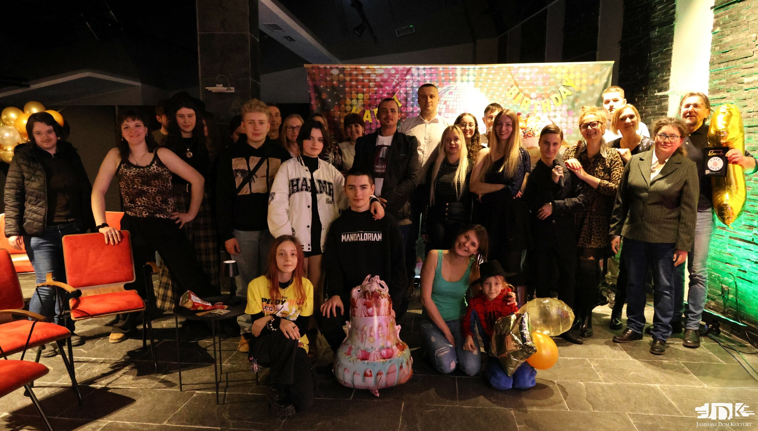 grupa uczestników karaoke pozuje do zdjęcia z balonami oraz uśmiechami na twarzach