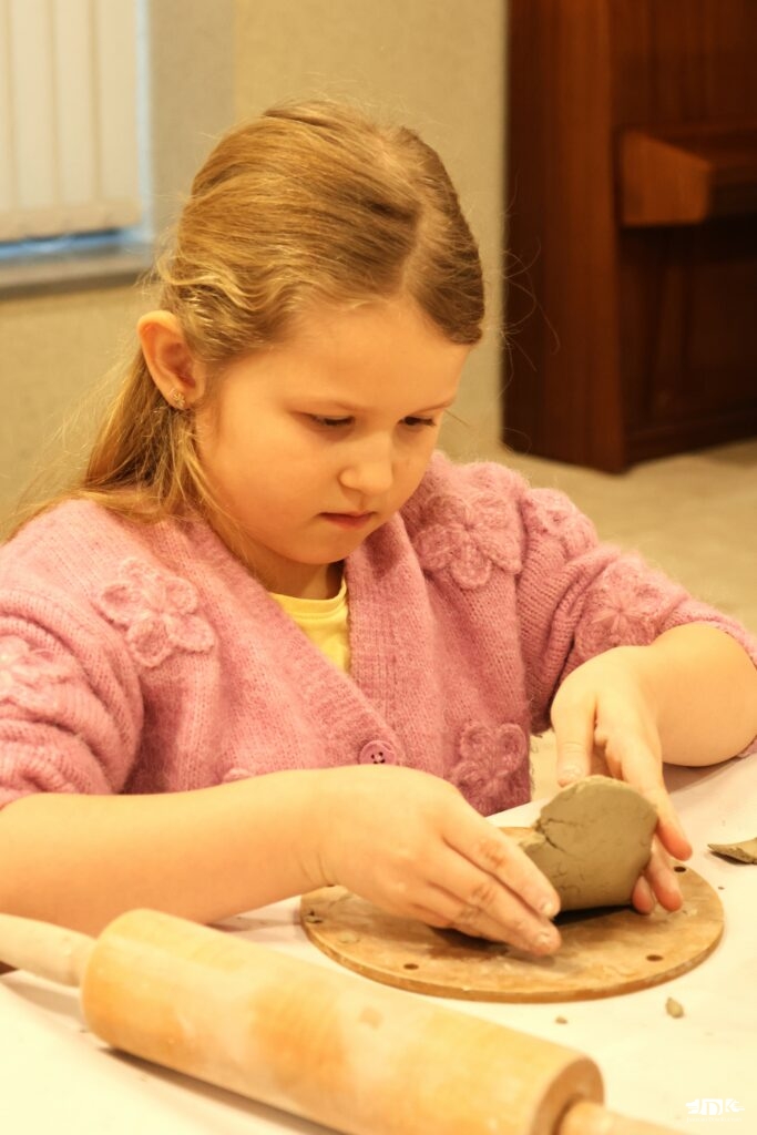dziewczynka lepiąca w glinie z wałkiem obok