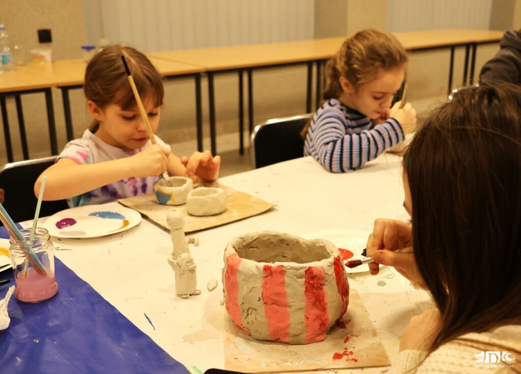 uczestnicy warsztatów malują różne formy - doniczkę w paski i miseczki