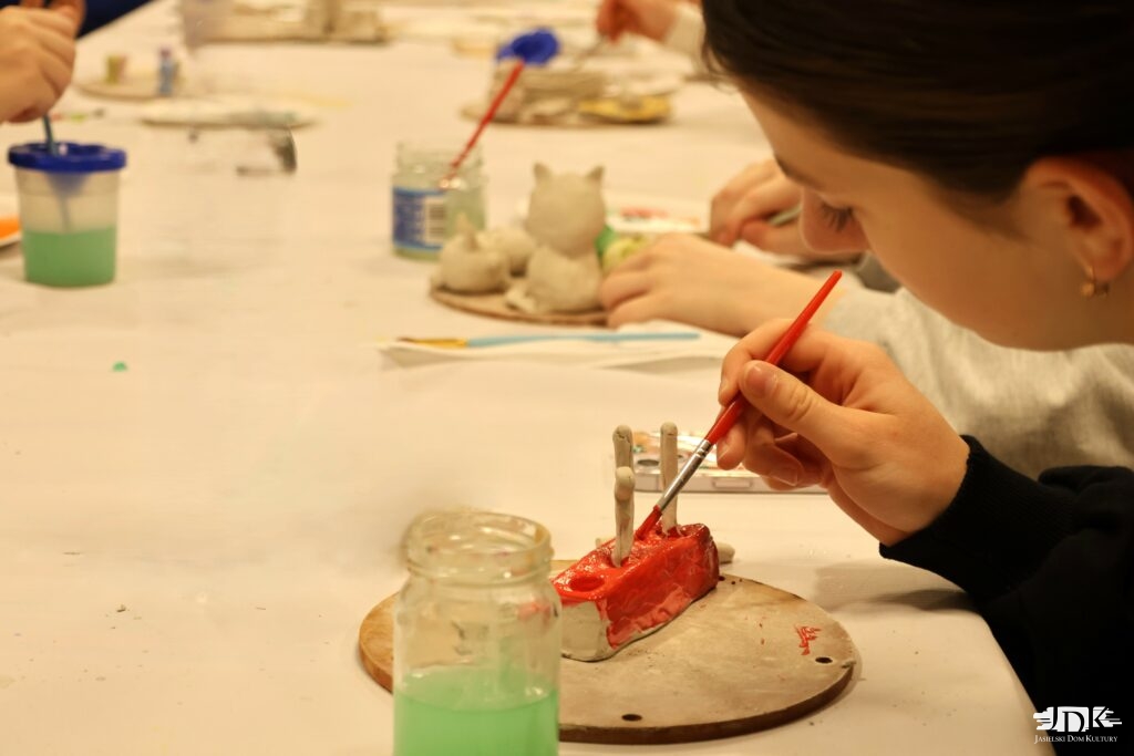 uczestniczka warsztatów malująca figurkę z gliny