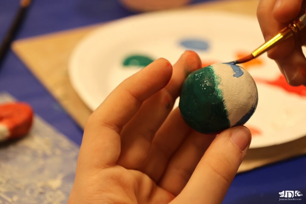 zielono-biała kulka z gliny w dłoni