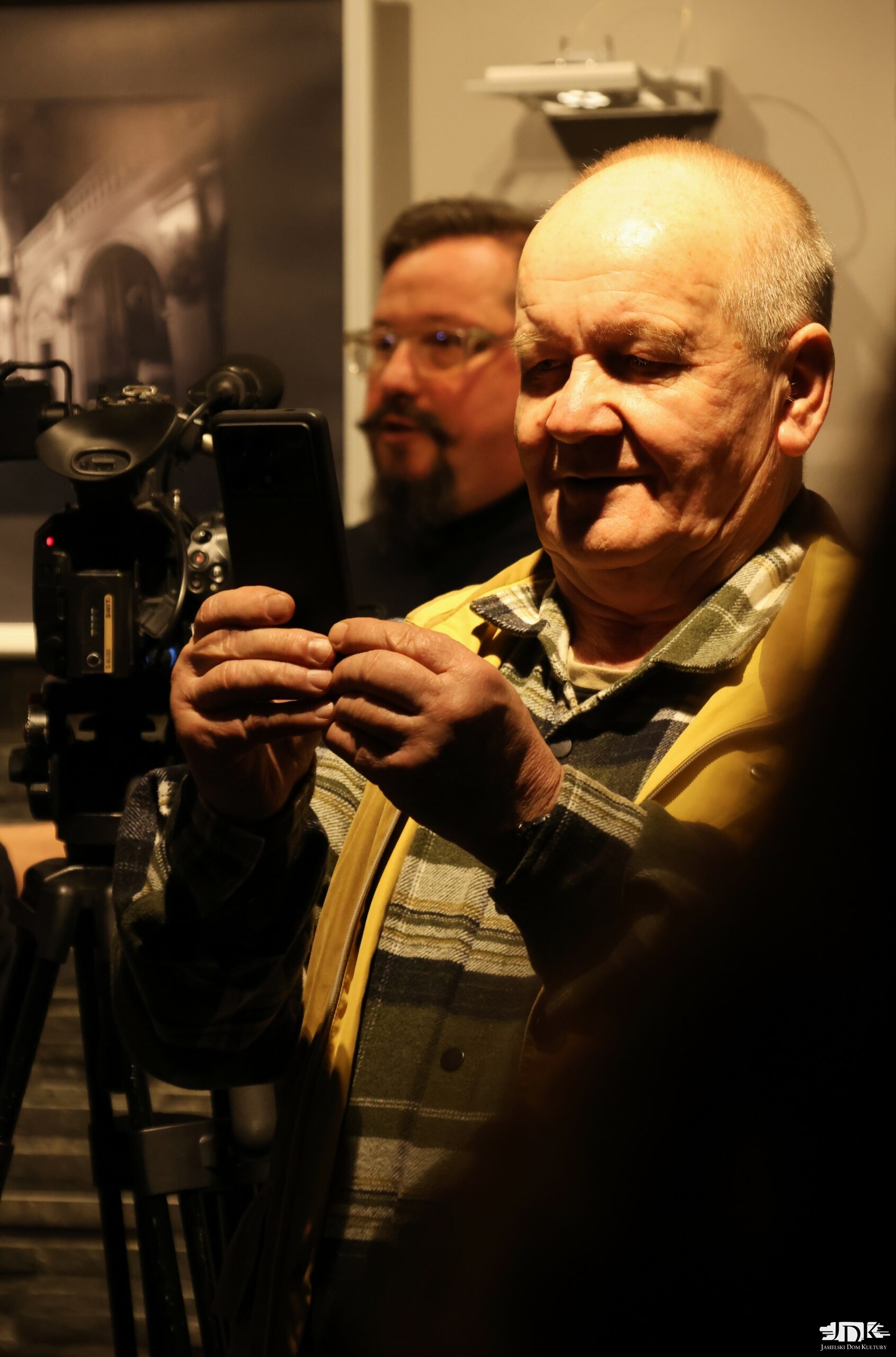 starszy pan robiący zdjęcia, w tle autor wystawy